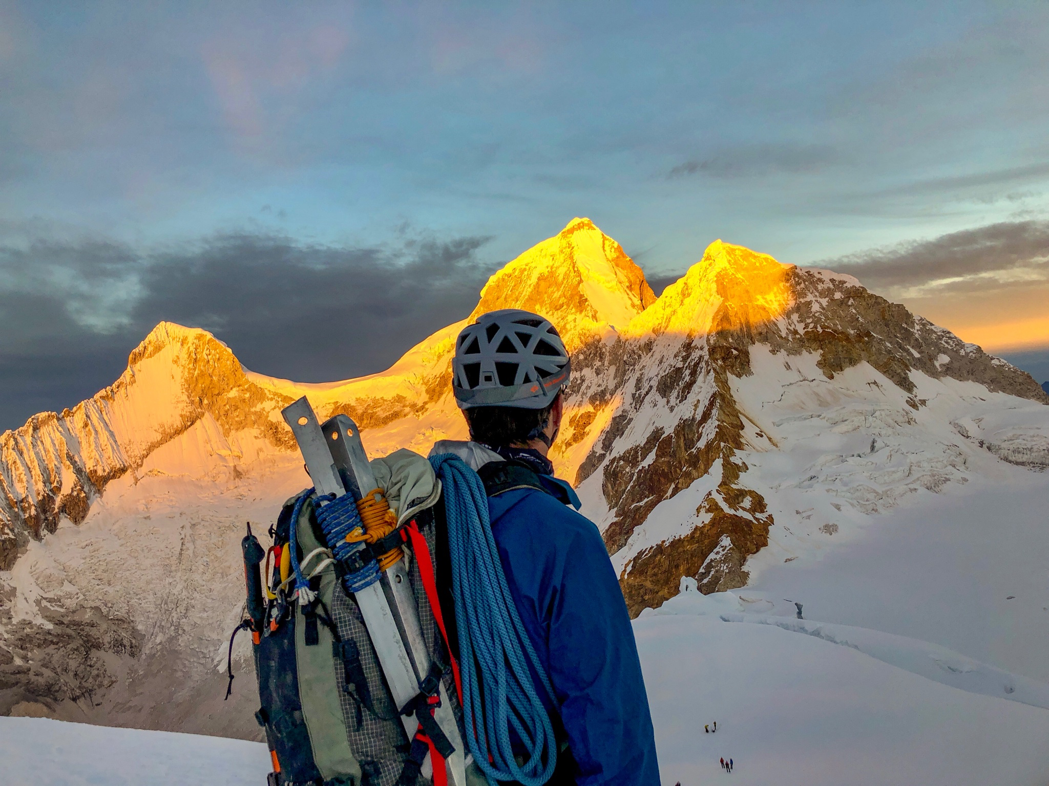 Man with climbing gear looking at sun rise on mountains