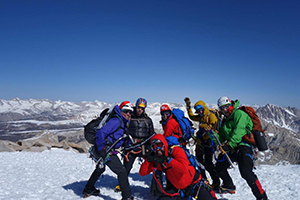 Group of people in helmets and winter coats on a snow coated mountain summit